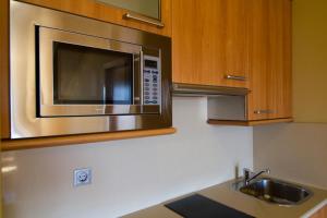 a kitchen with a stainless steel microwave and a sink at Apartamentos Esperanza del Mar in Portonovo