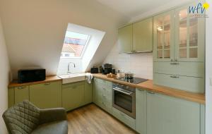 a kitchen with green cabinets and a sink and a window at Haus Casper Ferienwohnung 4 in Langeoog