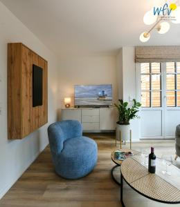 a living room with a blue chair and a tv at Haus Casper Ferienwohnung 2 in Langeoog