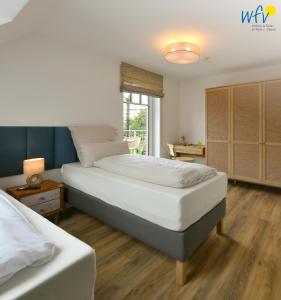 a bedroom with two white beds and a window at Haus Casper Ferienwohnung 2 in Langeoog