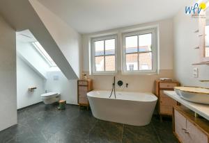 a bathroom with a large white tub and a toilet at Haus Casper Ferienwohnung 2 in Langeoog +32 photos
