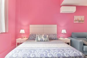 ein rosafarbenes Schlafzimmer mit einem Bett und einem blauen Stuhl in der Unterkunft Estudio Arena, A Pie De Playa in Cádiz