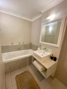 un bagno con un lavandino, una vasca e uno specchio di Modern self-catering apartment in a secure estate a Plettenberg Bay