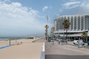 ein Strand mit einem großen Gebäude und Palmen in der Unterkunft Estudio Arena, A Pie De Playa in Cádiz