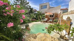a small swimming pool in a garden with pink flowers at Tropical Lodge SPA Narbonne in Narbonne
