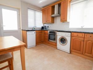 a kitchen with wooden cabinets and a washer and dryer at Bryn Bach in Colwyn Bay