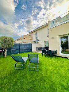 a yard with chairs and tables and a house at Maison proche plage in Villeneuve-lès-Maguelonne