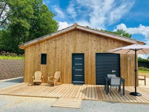 a wooden building with a table and an umbrella at La maison dans la prairie fleurie, espace et calme in Saint-Avit-Sénieur