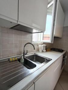 cocina con fregadero de acero inoxidable y ventana en A casa di Giulia near Rho Fiera, en Pero