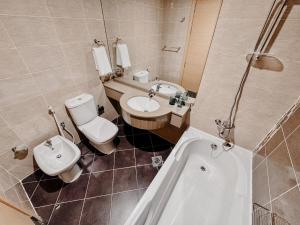 ein Badezimmer mit Toilette, Waschbecken und Badewanne in der Unterkunft Boho Chic Studio, Pool & Gym in Abu Dhabi