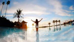 达穆尔JHotelResorts的身着白色衣服的女人站在游泳池里