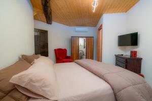 a bedroom with a large bed and a red chair at Casa di Zia Giovannina by Holiday World in Limina