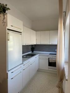 a kitchen with white cabinets and a white refrigerator at Zentrale Wohnung mit Georgenblick in Untermicheldorf