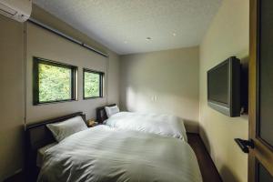 a bedroom with a bed and a flat screen tv at 森寧monet in Minami Aso