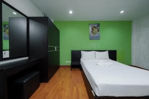 a bedroom with a bed and a green wall at Dancenter Khaosan Park Hotel in Bangkok