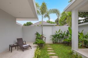 a patio with a chair and a palm tree at Silk Villa - 3 Bedrooms - Pool - Central Area in Bophut