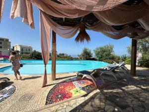 a woman walking by a pool with chairs and an umbrella at Apartment Olive in Dhërmi