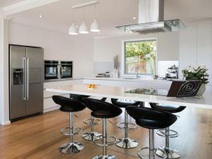 新普利茅斯Magic on Molesworth - 2BR townhouse near CBD的厨房设有黑色凳子,大白岛
