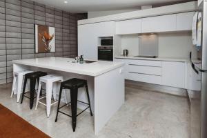 una cocina blanca con una gran isla blanca con taburetes en Perfect On Powderham Prime Inner City Location, en New Plymouth