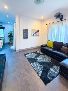 a living room with a black leather couch and a rug at Tropical 2 Bedroom Pool House In Central Location in Hua Hin