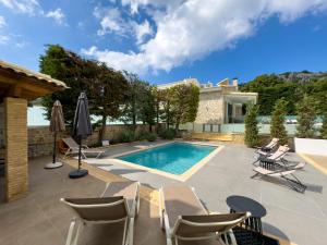 a swimming pool with chairs and a house at Shemesh Residence in Nafplio
