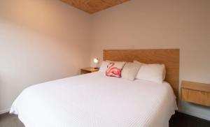 a bedroom with a white bed with a wooden headboard at The Dunes At Fitzroy Beach - Unit 3 in New Plymouth
