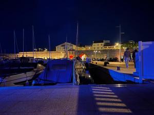 une marina la nuit avec des gens marchant sur un quai dans l'établissement Location, à Antibes