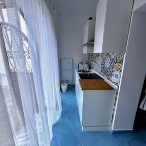 a white kitchen with a sink and a window at Maison Emi in Montecorice