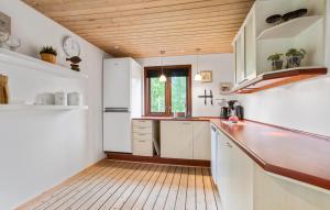 a kitchen with white cabinets and a wooden ceiling at 2 Bedroom Lovely Home In Skagen in Skagen