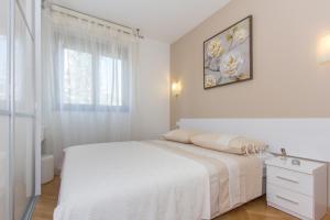 a white bedroom with a bed and a window at Apartment Luce in Split