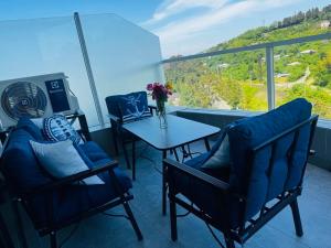 a balcony with two chairs and a table with a vase of flowers at Sunset Residence Bamboo Beach Tsikhisdziri in Ts'ikhisdziri