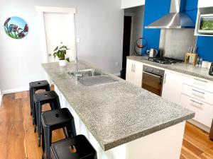 a kitchen with a sink and a counter with stools at Huatoki Hideaway Peaceful Central Location in New Plymouth