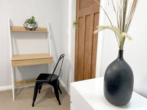 a black vase sitting on a white table with a chair at Huatoki Hideaway Peaceful Central Location in New Plymouth