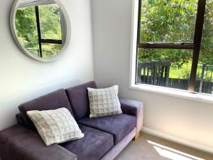 a purple couch in a room with a mirror at Huatoki Hideaway Peaceful Central Location in New Plymouth +8 photos