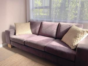 a brown couch with two pillows in a living room at Huatoki Hideaway Peaceful Central Location in New Plymouth +4 photos