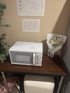 Un microondas sobre una mesa con un ramo de flores. en e-hostel 心斎橋 403, en Osaka