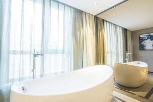 un bagno con vasca bianca e una grande finestra di TRUE GO Hotel Bejing Sanyuangiao Yansha a Pechino
