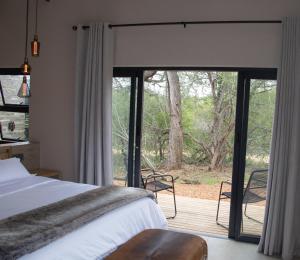 Un dormitorio con una cama y una puerta corrediza de vidrio. en Villa Tau, en Hoedspruit 34 fotos más