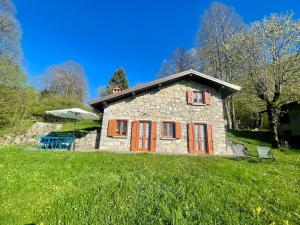 a stone house with orange doors on a green field at Il Casello Bigallo in Esino Lario