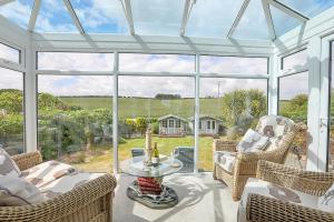 a conservatory with wicker chairs and a table at Finest Retreats - Shoe Buttons Cottage at Gap Road in Reighton