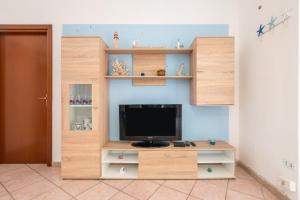 a living room with a tv in a wooden entertainment center at Casa Vacanze 4 Venti in Muravera