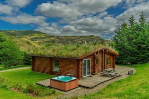 a cabin with a grass roof with a hot tub at Finest Retreats - Cragdhu Log Cabin in Glenshee
