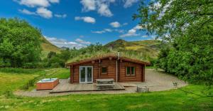 a small wooden cabin with a grass roof at Finest Retreats - Cragdhu Log Cabin in Glenshee