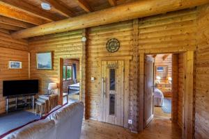 a living room with a couch and a tv at Finest Retreats - Cragdhu Log Cabin in Glenshee