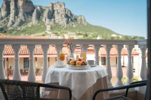 a table with a bowl of fruit and drinks on a balcony at Hotel Kaikis in Kalabaka