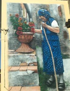 a painting of a woman watering a vase of flowers at Smaria Del Monte in Rosora