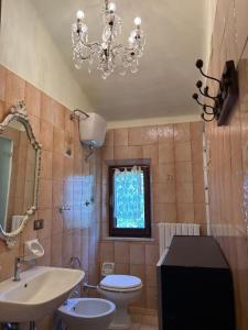 a bathroom with a sink toilet and a chandelier at Smaria Del Monte in Rosora