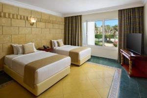 a hotel room with two beds and a flat screen tv at Palm Royale Resort - Soma Bay in Hurghada