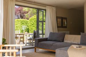 a living room with a couch and a sliding glass door at A Luxury Retreat in the Cotswolds in Cheltenham +29 photos