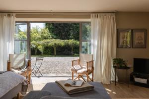 a bedroom with a bed and chairs and a sliding glass door at A Luxury Retreat in the Cotswolds in Cheltenham